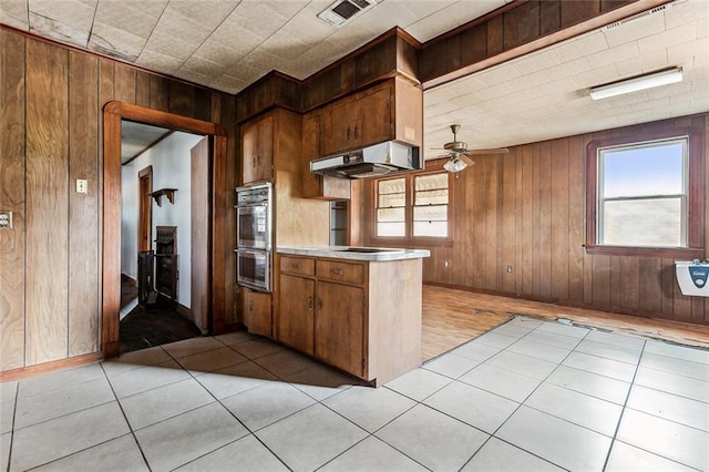 kitchen featuring double oven, extractor fan, ceiling fan, and a healthy amount of sunlight