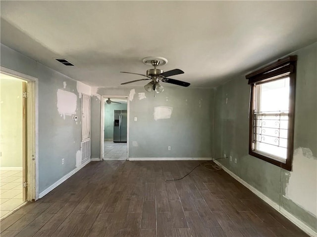 unfurnished room with ceiling fan, wood finished floors, visible vents, and baseboards