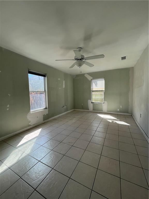 spare room featuring light tile patterned floors, visible vents, and a wealth of natural light