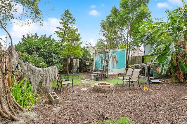 view of yard featuring a shed, fence, a fire pit, and an outdoor structure