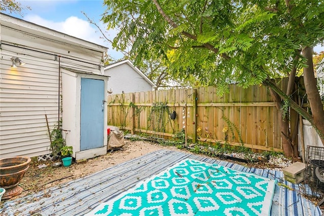 view of patio featuring a fenced backyard, an outdoor structure, and a shed