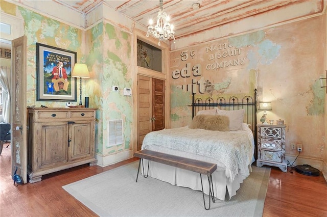 bedroom with dark hardwood / wood-style floors and an inviting chandelier