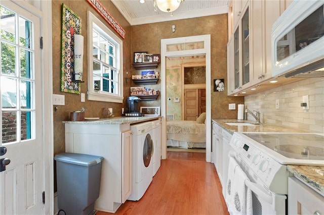 interior space with light wood-type flooring, washer / clothes dryer, ornamental molding, and sink