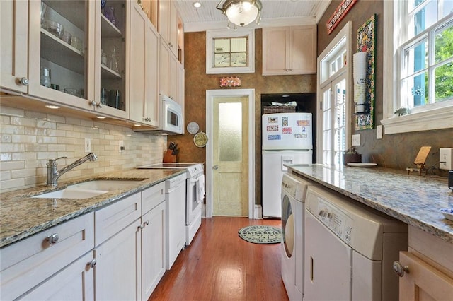 kitchen with light stone countertops, sink, hardwood / wood-style floors, and white appliances