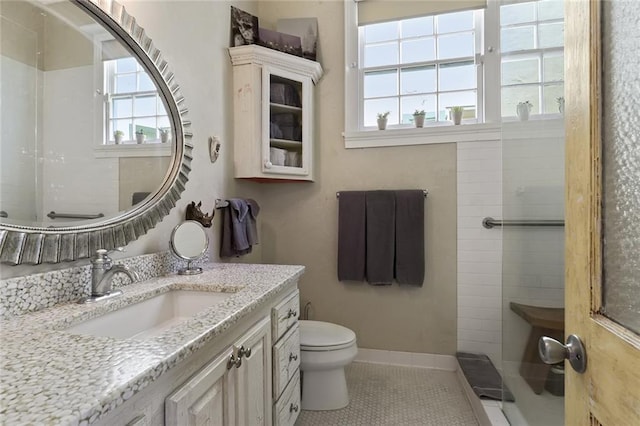 bathroom with toilet, plenty of natural light, vanity, and tile patterned flooring