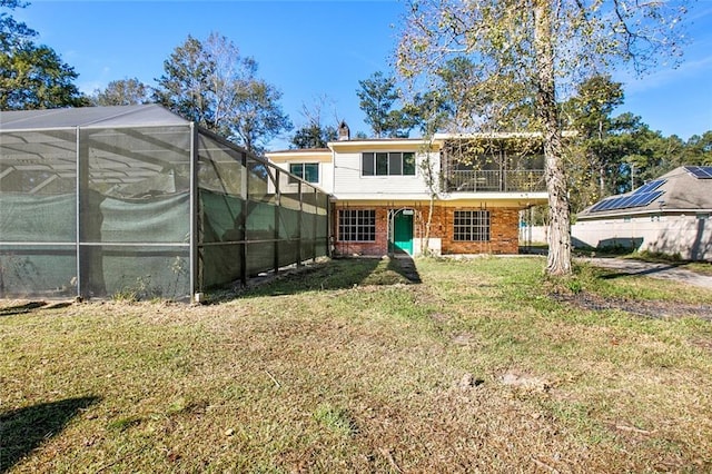 rear view of house featuring a lawn and glass enclosure