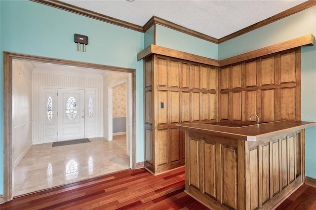 foyer entrance with a textured ceiling, crown molding, and dark wood-type flooring