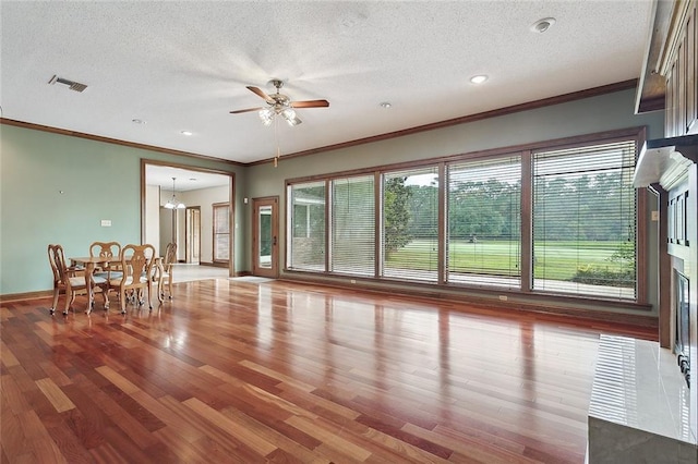 unfurnished living room featuring ceiling fan with notable chandelier, a textured ceiling, hardwood / wood-style flooring, and crown molding