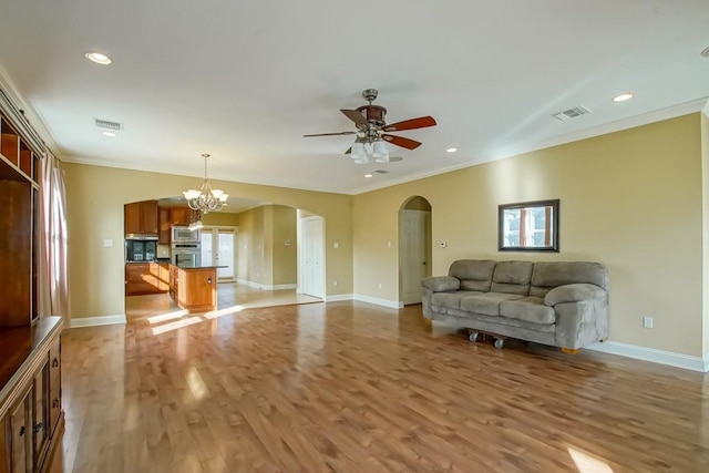 unfurnished living room featuring a wealth of natural light, crown molding, light hardwood / wood-style flooring, and ceiling fan with notable chandelier