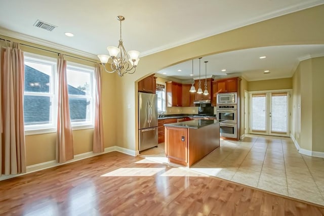 kitchen featuring a wealth of natural light, stainless steel appliances, a kitchen island, and hanging light fixtures