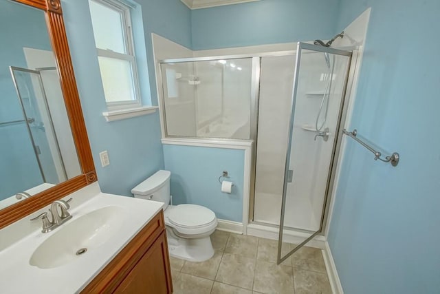 bathroom with tile patterned floors, a shower with door, vanity, and toilet