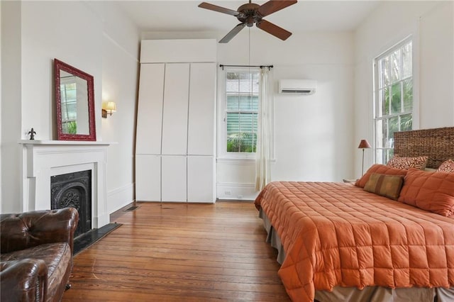 bedroom featuring hardwood / wood-style flooring, ceiling fan, and a wall mounted AC