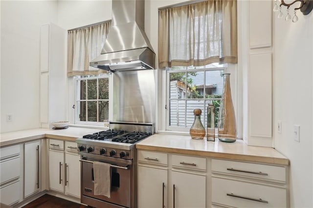 kitchen with white cabinetry, wall chimney exhaust hood, and stainless steel stove