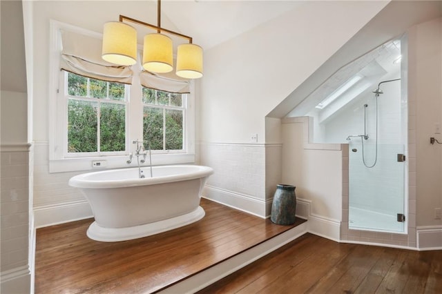 bathroom featuring separate shower and tub, lofted ceiling with skylight, wood-type flooring, and tile walls