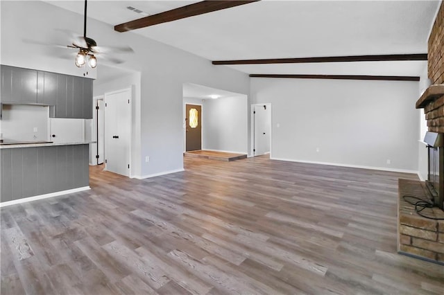 unfurnished living room featuring light wood-type flooring, lofted ceiling with beams, ceiling fan, and a fireplace