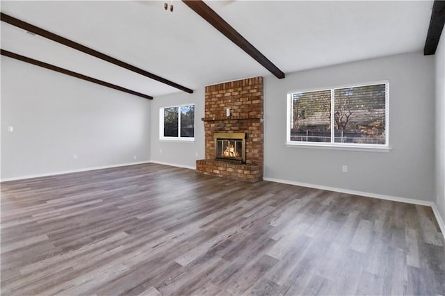 unfurnished living room with a brick fireplace, wood-type flooring, and lofted ceiling with beams