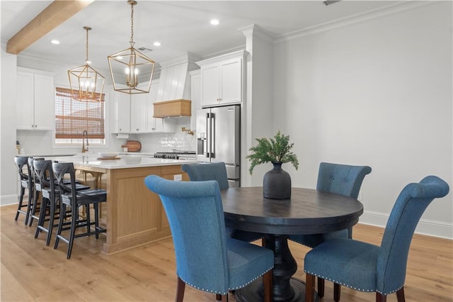 dining area featuring crown molding, light wood-type flooring, and beam ceiling