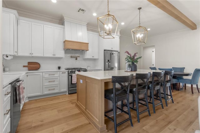 kitchen featuring a center island, stainless steel appliances, white cabinetry, and a notable chandelier