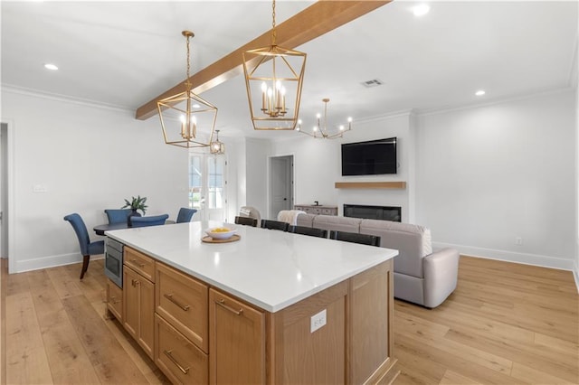 kitchen with a kitchen island, stainless steel microwave, beamed ceiling, and hanging light fixtures