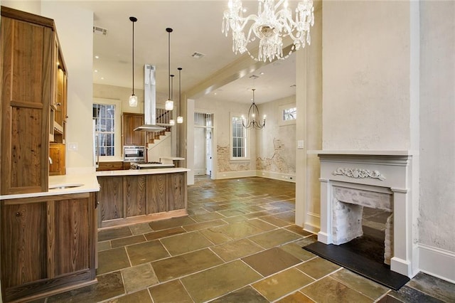 kitchen featuring sink, decorative light fixtures, a premium fireplace, a notable chandelier, and island range hood