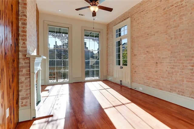 doorway with hardwood / wood-style flooring, ceiling fan, and a fireplace