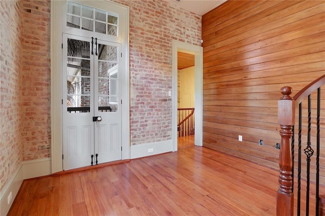 interior space with wooden walls, light hardwood / wood-style floors, and brick wall