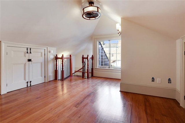 additional living space with hardwood / wood-style floors and vaulted ceiling