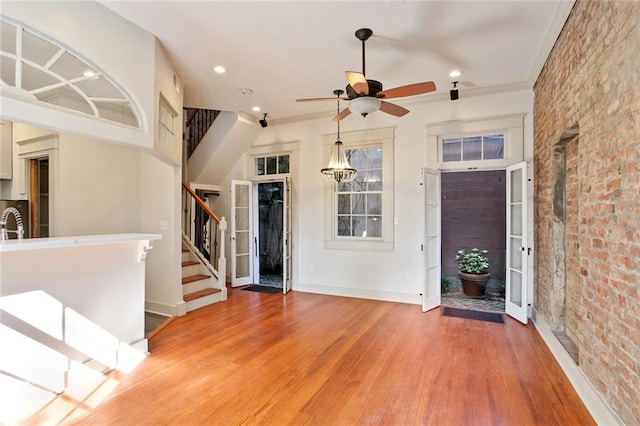 foyer entrance featuring ceiling fan, ornamental molding, brick wall, and hardwood / wood-style flooring