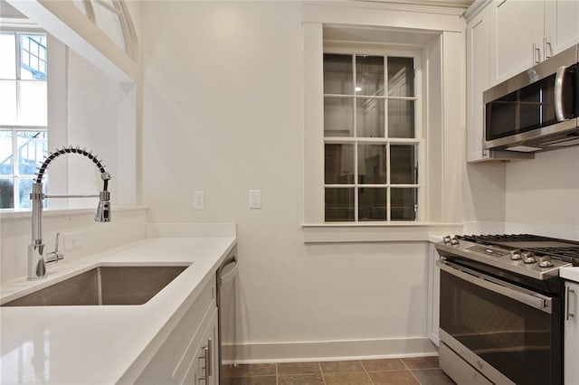 kitchen with white cabinetry, sink, dark tile patterned floors, and stainless steel appliances