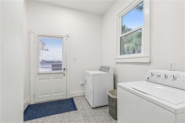 washroom with light tile patterned floors, washer and clothes dryer, and a healthy amount of sunlight