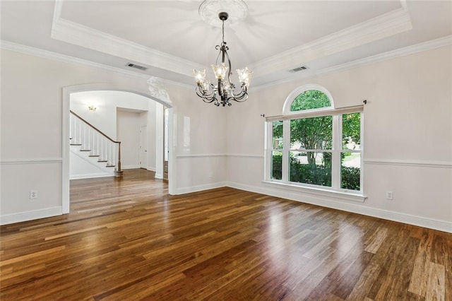 empty room featuring a raised ceiling, crown molding, a chandelier, and dark hardwood / wood-style floors