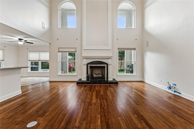 unfurnished living room featuring a healthy amount of sunlight, a high ceiling, and wood-type flooring