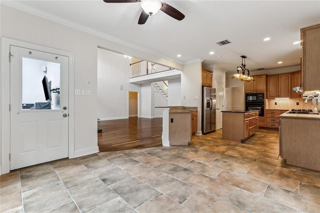 kitchen featuring backsplash, ceiling fan with notable chandelier, black appliances, decorative light fixtures, and a center island