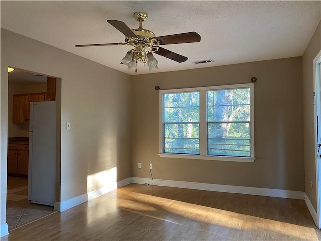 empty room featuring ceiling fan, light hardwood / wood-style floors, and a textured ceiling