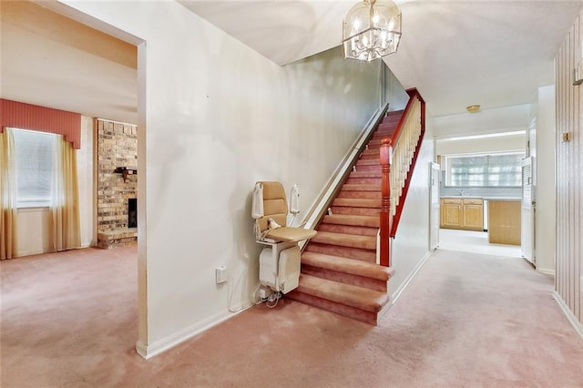 stairway featuring carpet floors, an inviting chandelier, and a fireplace