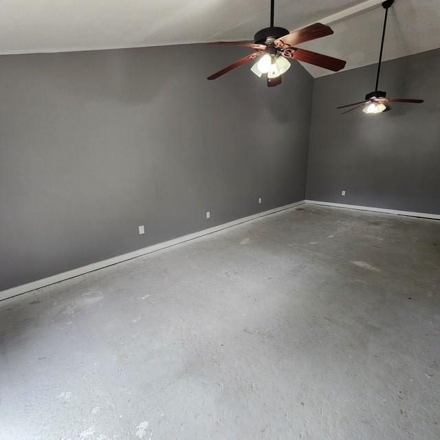 unfurnished room with vaulted ceiling, concrete floors, and baseboards