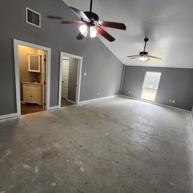 unfurnished bedroom with lofted ceiling, visible vents, baseboards, and ensuite bathroom