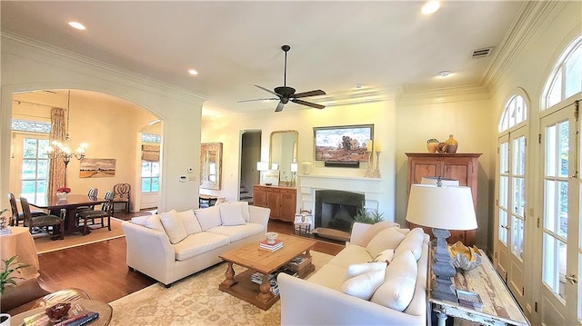 living room with crown molding, plenty of natural light, ceiling fan with notable chandelier, and hardwood / wood-style flooring