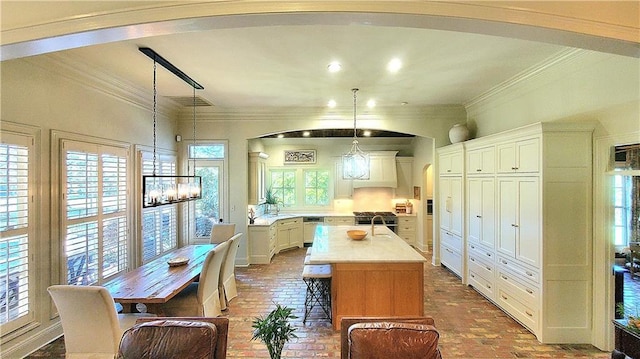 kitchen with white cabinets, plenty of natural light, a kitchen island, and hanging light fixtures