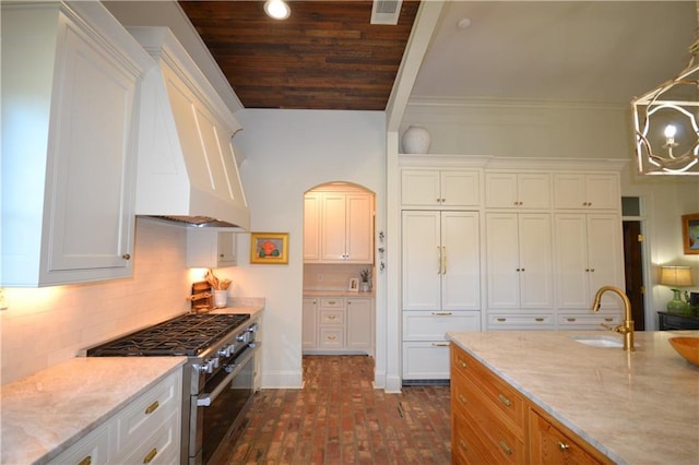 kitchen with white cabinets, decorative light fixtures, light stone counters, and high end stainless steel range oven