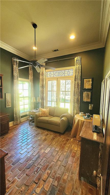 living area featuring ceiling fan and crown molding