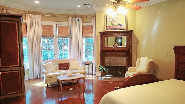 sitting room featuring hardwood / wood-style flooring, ceiling fan, crown molding, and a tiled fireplace