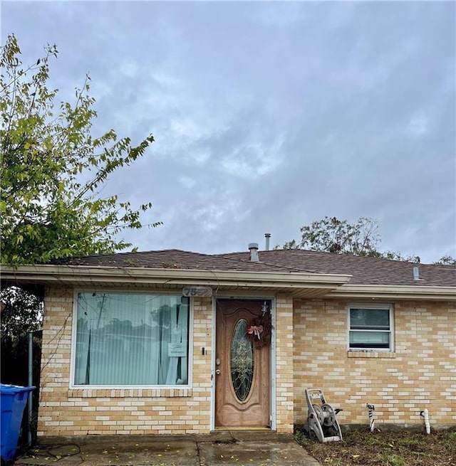 view of front of house with brick siding and a shingled roof