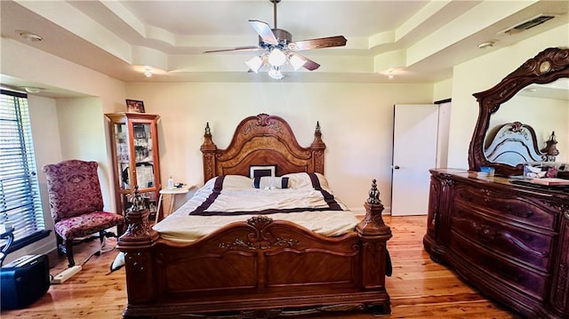 bedroom featuring a tray ceiling, ceiling fan, and light hardwood / wood-style floors