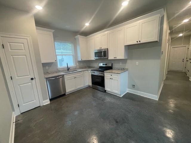 kitchen featuring white cabinets, appliances with stainless steel finishes, light stone counters, and sink