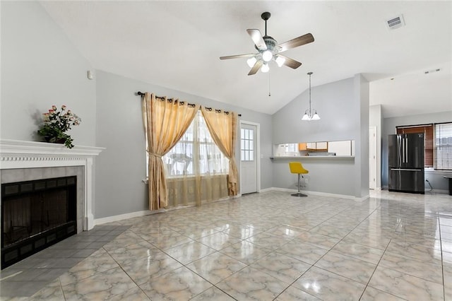 unfurnished living room with a fireplace, ceiling fan with notable chandelier, vaulted ceiling, and a healthy amount of sunlight