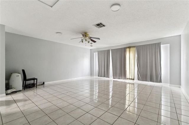 tiled empty room with ceiling fan and a textured ceiling