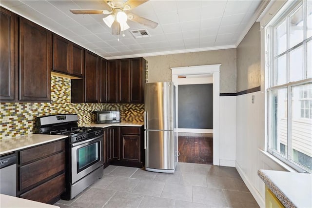 kitchen with decorative backsplash, ornamental molding, dark brown cabinets, light tile patterned flooring, and stainless steel appliances