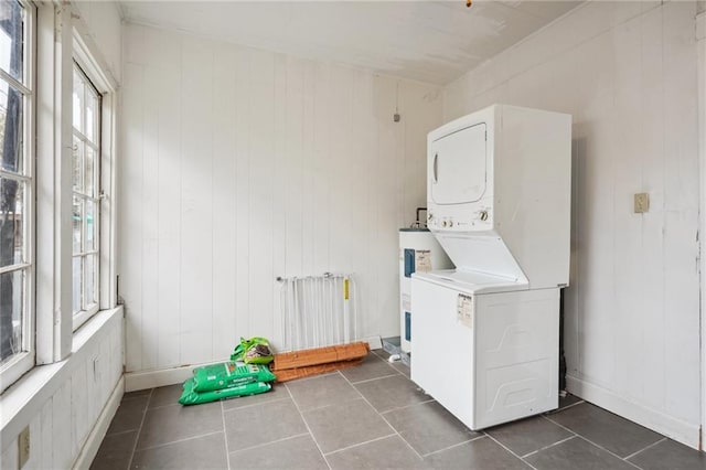 50507 Passera Ct, New Orleans, LA 70119 - laundry area with stacked washer and clothes dryer, water heater, dark tile patterned floors, and wood walls