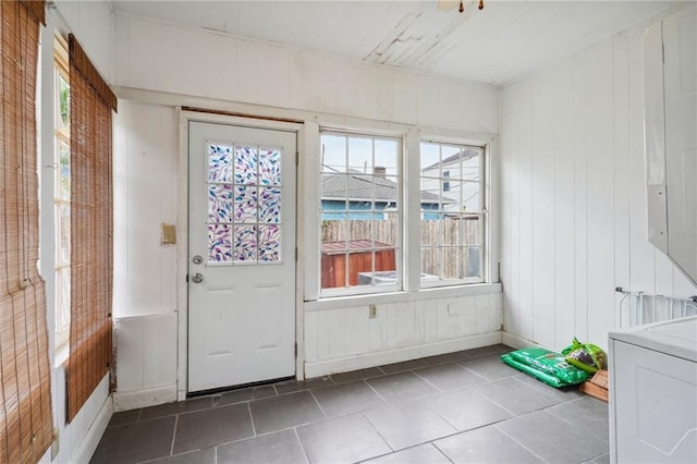 doorway featuring wood walls, dark tile patterned flooring, and washer / dryer